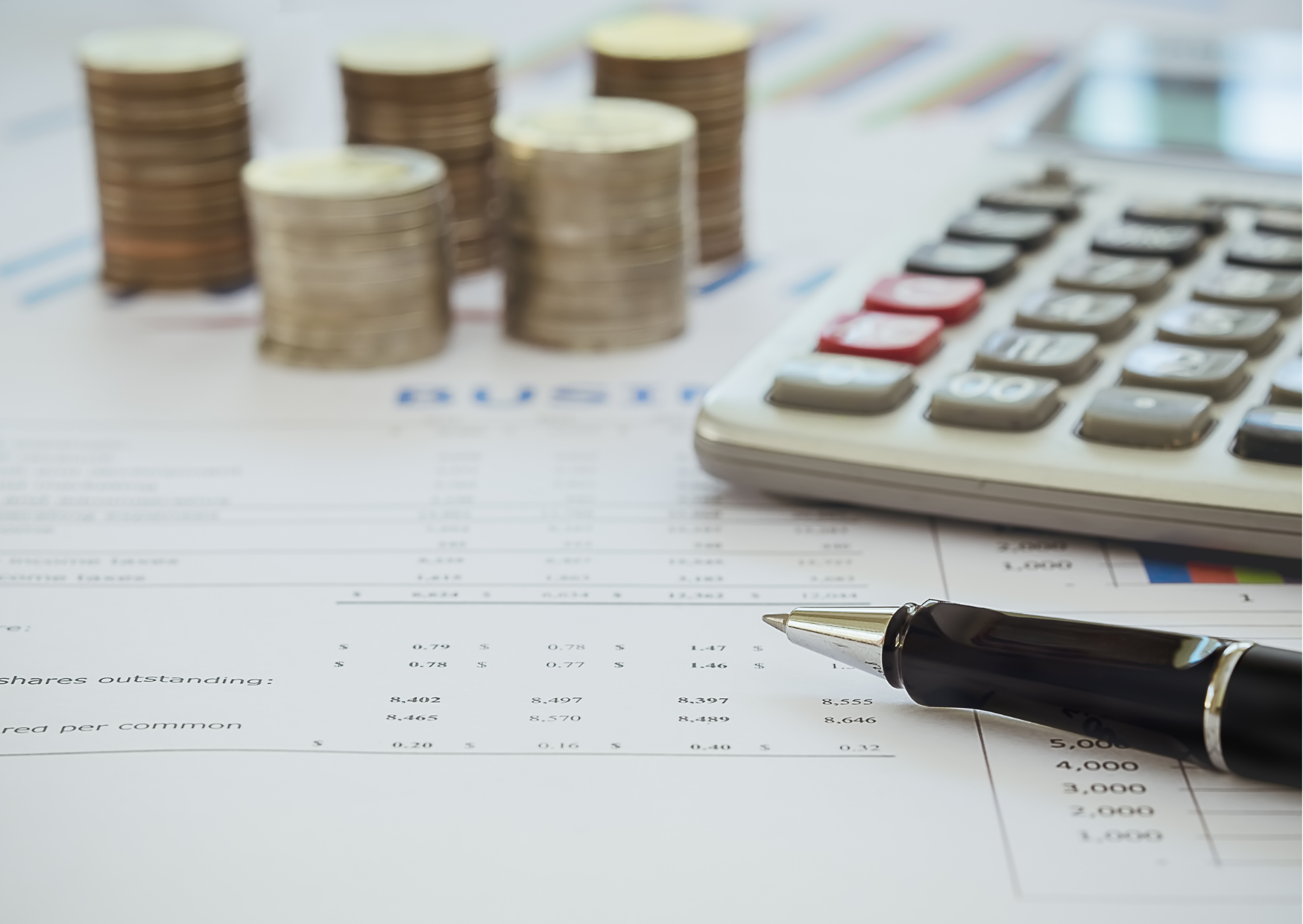 table with close up of bank statements, coins, calculator and pen